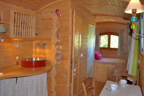 una cocina en una cabaña de madera con fregadero y ventana en La roulotte Chic et Boheme, en Mazan