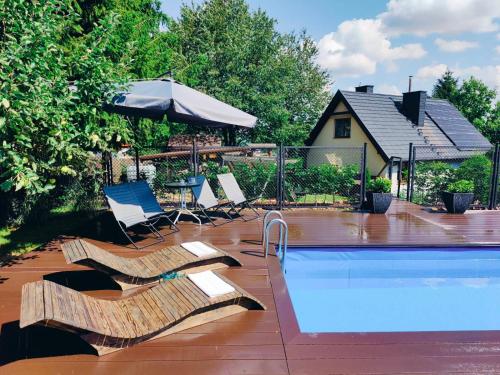 a pool with chairs and an umbrella next to a house at Chata Na Krańcu Świata in Łączna