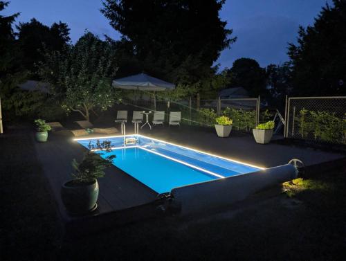 a swimming pool with lights in a backyard at night at Chata Na Krańcu Świata in Łączna