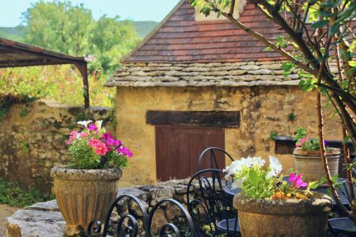 Un edificio de piedra con dos jarrones con flores. en La Petite Maison- Fairytale Stay in Village Center, en Beynac-et-Cazenac