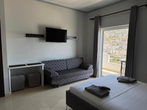 a room with a bed and a couch and a television at Apartments Klajdi in Sarandë
