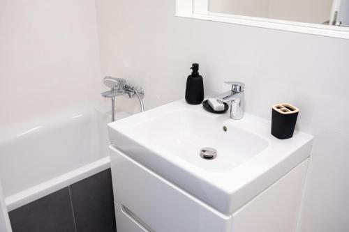 ein weißes Badezimmer mit Waschbecken und Badewanne in der Unterkunft Stylish Poprad Stay - 10min to High Tatras & Parking in Poprad