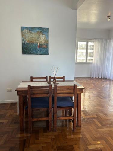 a dining room table with chairs and a painting on the wall at Departamento amplio Olivos 