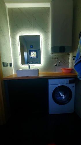 a bathroom with a mirror and a washing machine at Mazurskie Wzgórze Nad Jeziorem Isąg in Pelnik