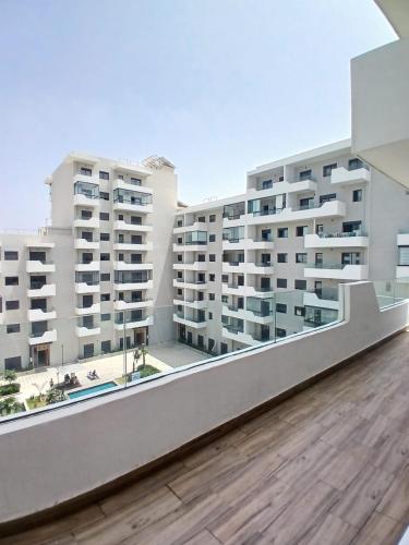 einen Balkon mit Blick auf zwei Apartmentgebäude in der Unterkunft Duplex Luxe 3 Chambres Vue Mer & Piscine à Zenata Eco City in Aïn Harrouda