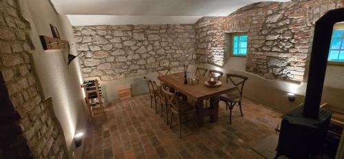 a dining room with a table and a stone wall at Hájovna u Jindřicha in Nová Pec
