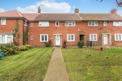 a large red brick house with a grass yard at Spacious 3BHK near Heathrow in Cranford