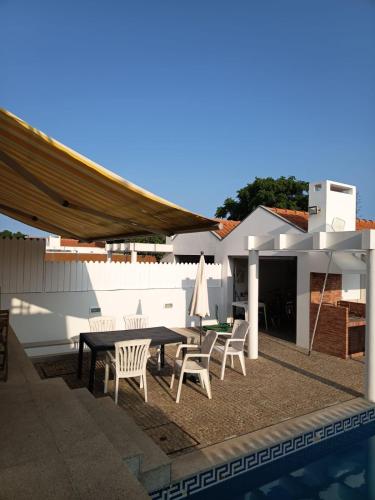 a patio with a table and chairs next to a pool at Villa Nenúfares in Torreira