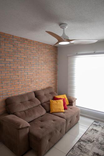 a brown couch in a living room with a ceiling fan at B&B Apartamento acolhedor Bem localizado, Próximo ao aeroporto in São José dos Pinhais
