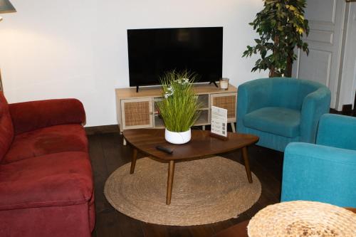 a living room with a tv and two chairs and a coffee table at Domaine de Brise Bois - Chambres & Gîtes in Rouzède