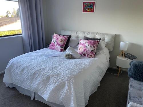 a bedroom with a white bed with pink pillows at Quiet and cosy in Waikanae