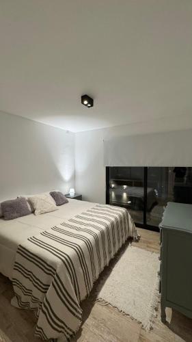 a white bedroom with a large bed and a window at Departamento en Rojas in Rojas