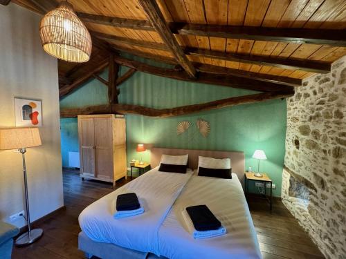 a bedroom with a large bed in a room with wooden ceilings at Domaine de Brise Bois - Chambres & Gîtes in Rouzède
