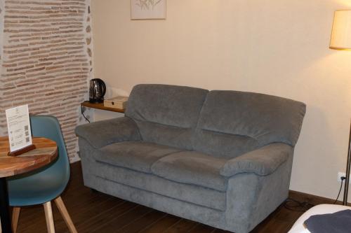a couch in a living room with a table and a chair at Domaine de Brise Bois - Chambres & Gîtes in Rouzède