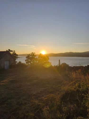 a sunset over the water with a house in a field at New Riyork Sweet Home in Geres