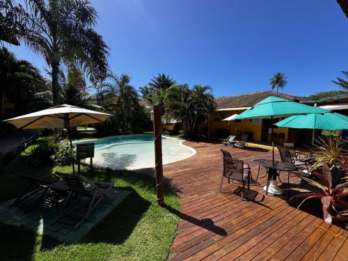 a deck with chairs and umbrellas next to a pool at Pousada Tropicarim in Itacimirim