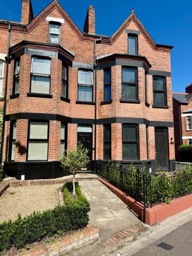 a large brick building with a gate in front of it at 4 Bedroom Belfast Townhouse in Belfast