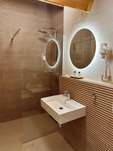 a bathroom with a sink and a shower and a mirror at Kalemi Twin Boutique Hotel in Gjirokastër