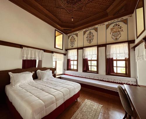a bedroom with a bed in a room with windows at Kalemi Twin Boutique Hotel in Gjirokastër