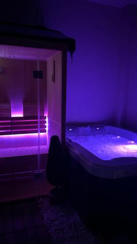 a dark room with a tub with purple lights at Duplex Luxe - Sauna & Jacuzzi Privatif in Montrouge