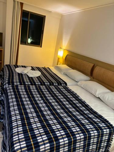 a large bed with a blue and white striped blanket at Flat Beach Class Resort Muro Alto in Porto De Galinhas
