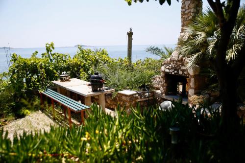 a table and bench with the ocean in the background at Villa Šoti in Mlini