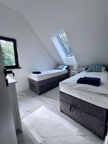 two beds in a room with two windows at Marina Dziwnow Premium Haus in Dziwnów