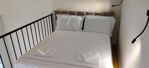 a bed with white sheets and pillows on it at Hana Apart-hotel in Sarandë