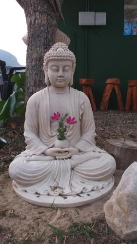 a statue of a buddha holding a flower at Camping luz do sol in Aiuruoca