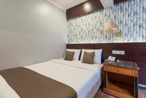 a small bedroom with a bed and a night stand at Hotel Grand Orchard in Gua Sai