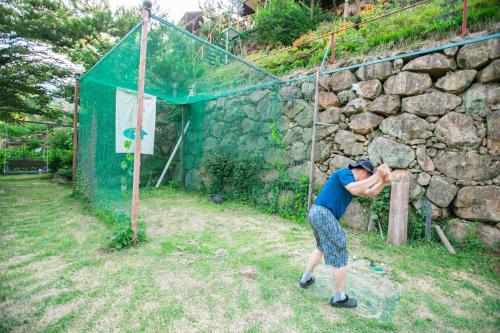 a person swinging a baseball bat against a stone wall at Jirisan One Night Two Days Pension in Gurye