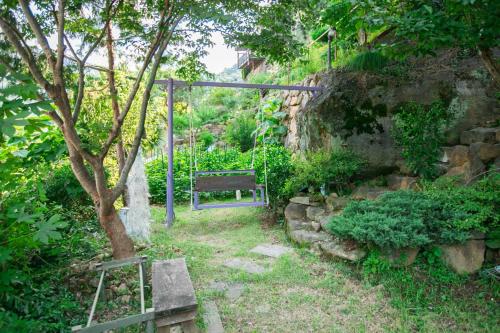 a bench sitting in a garden next to a stone wall at Jirisan One Night Two Days Pension in Gurye
