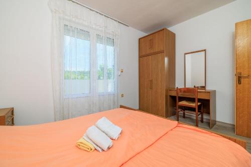 a bedroom with an orange bed with towels on it at Apartments Milorad M in Lopar