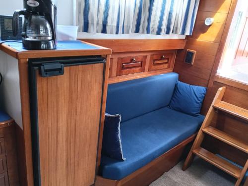 a small kitchen with a blue seat under a counter at Deluxe romantic boat in Hoogeveen