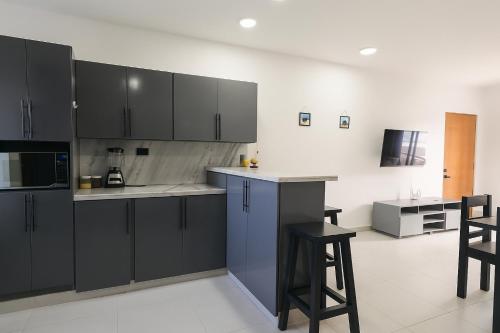 a kitchen with black cabinets and bar stools at Fully Serviced Apartment with 24h Power, Security and Wi-Fi in Sosúa