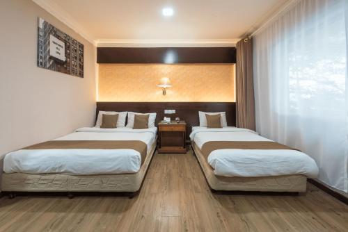 a hotel room with two beds and a window at Hotel Grand Orchard in Gua Sai