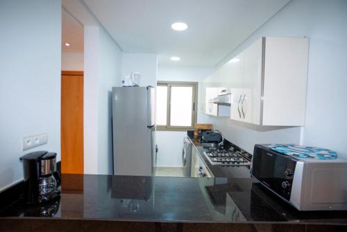 a kitchen with a refrigerator and a microwave at Chez Dany à Residence Beralmar in Asilah