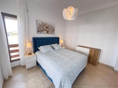 a bedroom with a blue bed and a window at La perle bleue de Beralmar Asilah in Oulad Akkou