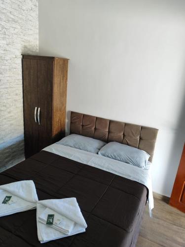 a bed with a brown headboard and a cabinet at Shamah Espaço in Catas Altas