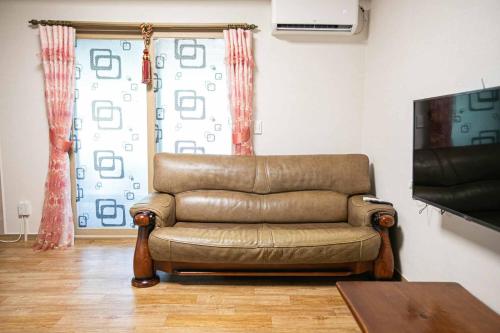 a brown leather couch in a living room with a television at Jirisan One Night Two Days Pension in Gurye