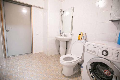 a bathroom with a toilet and a sink and a washing machine at Jirisan One Night Two Days Pension in Gurye