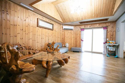 a living room with a glass table and wooden walls at Jirisan One Night Two Days Pension in Gurye