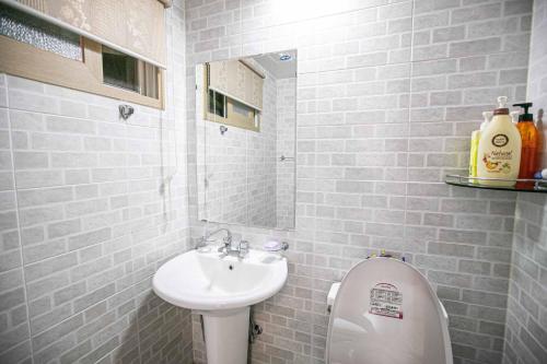 a bathroom with a sink and a toilet and a mirror at Jirisan One Night Two Days Pension in Gurye