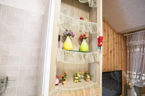 a shelf with three yellow vases and flowers on it at Jirisan One Night Two Days Pension in Gurye