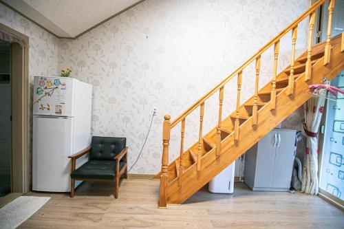 a staircase in a room with a chair and a refrigerator at Jirisan One Night Two Days Pension in Gurye