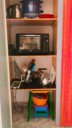 a kitchen shelf with a microwave and a stool at Riad SULTANA lateral seaview in Saidia 