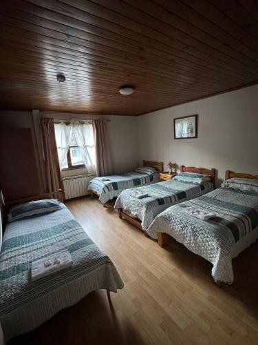 a room with three beds in a room at Hostal Rio Ona in Ushuaia