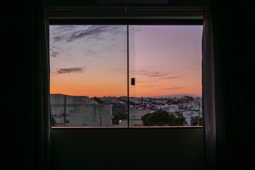 a window with a view of a city at sunset at Alvorada do Lago - A melhor hospedagem de Umuarama in Umuarama