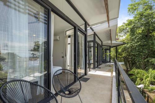 a balcony with two chairs and glass doors at L'Avventura in Tamarindo