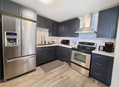 a kitchen with black cabinets and stainless steel appliances at Spacious 3-Bedroom Home. in Regina